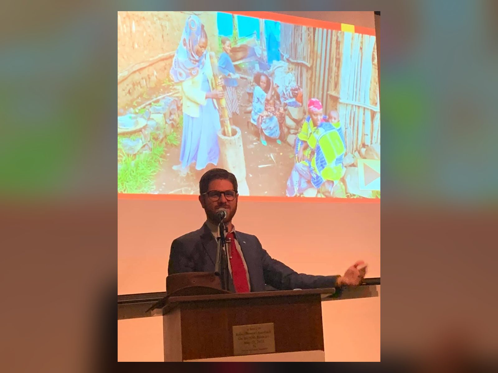 A.Y. Katsof at the microphone in front of a projected photo of an Ethiopian Jewish family, during his Atlanta talk.