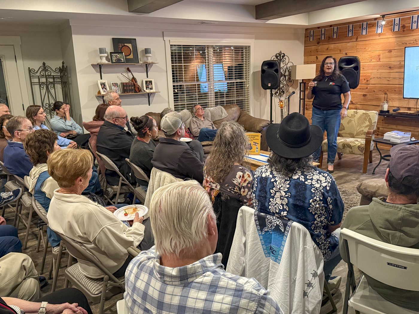 A speaker presents to a seated audience at an Atlanta Israel Coalition community evening.