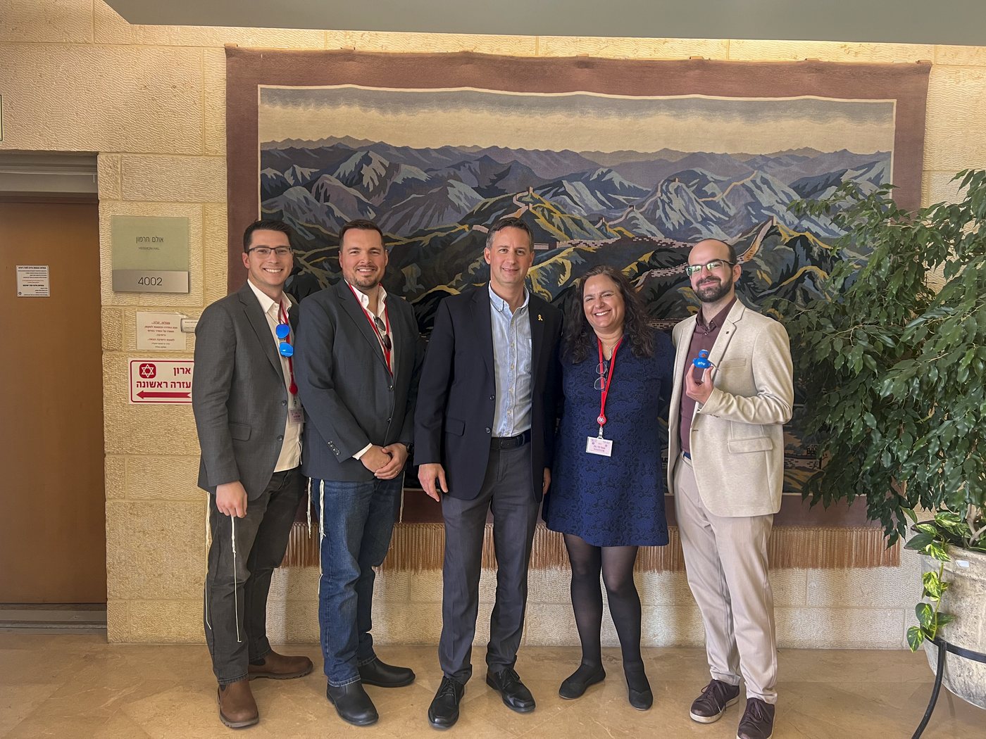 An Atlanta Israel Coalition delegation gathers for a group photo in front of a mural of the Israeli landscape.