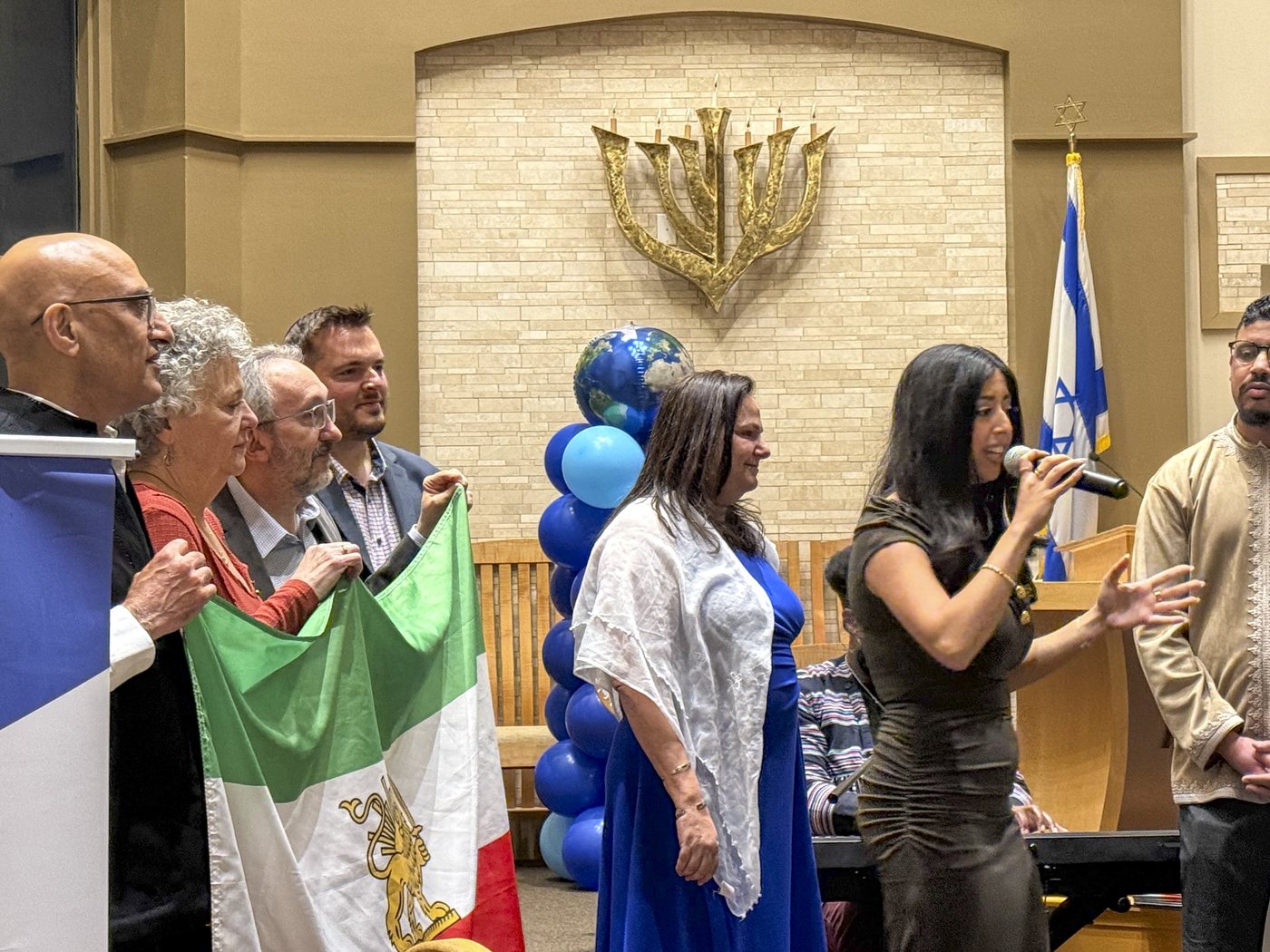 Community members raise flags and sing at an Atlanta Israel Coalition solidarity gathering.