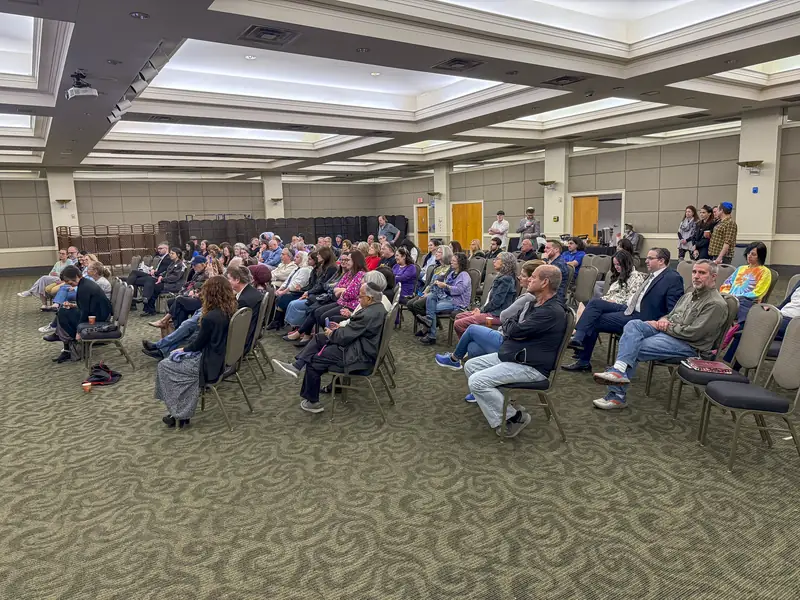 A hotel ballroom full of guests seated in rows at an AIC community briefing.