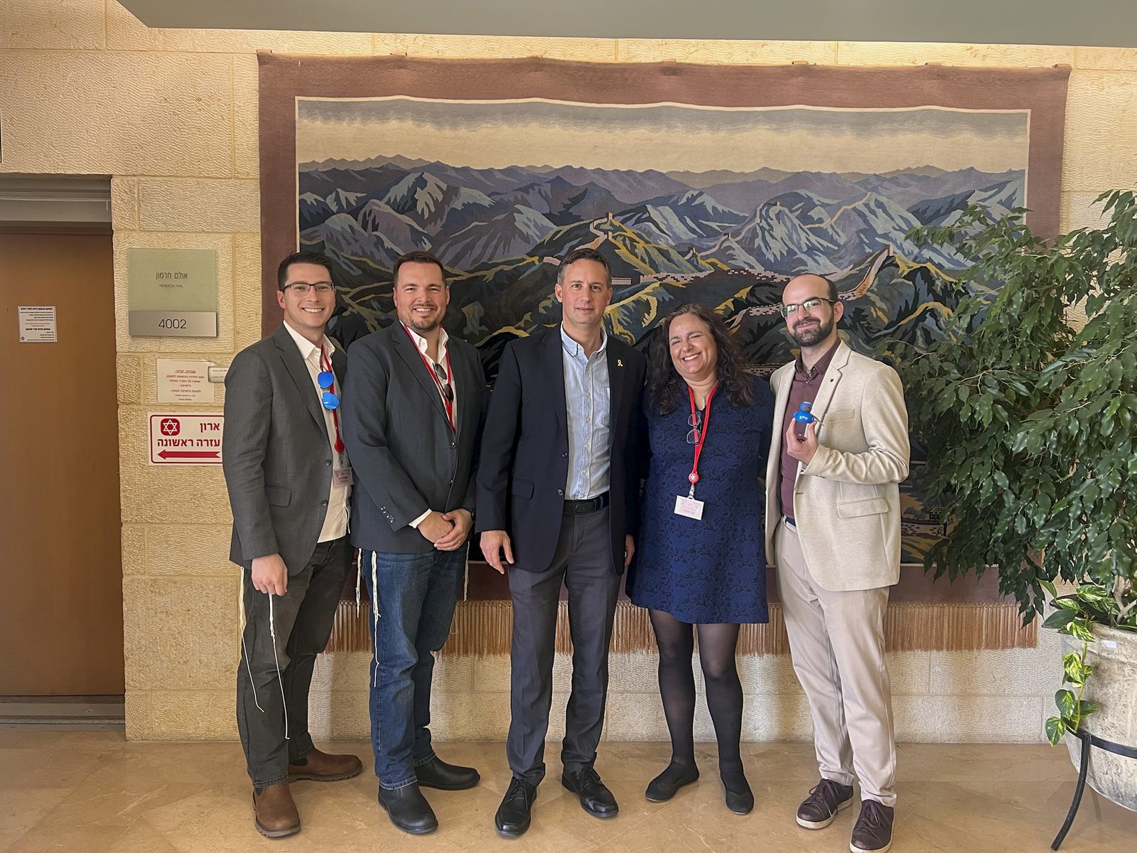 An Atlanta Israel Coalition delegation gathers for a group photo in front of a mural of the Israeli landscape.