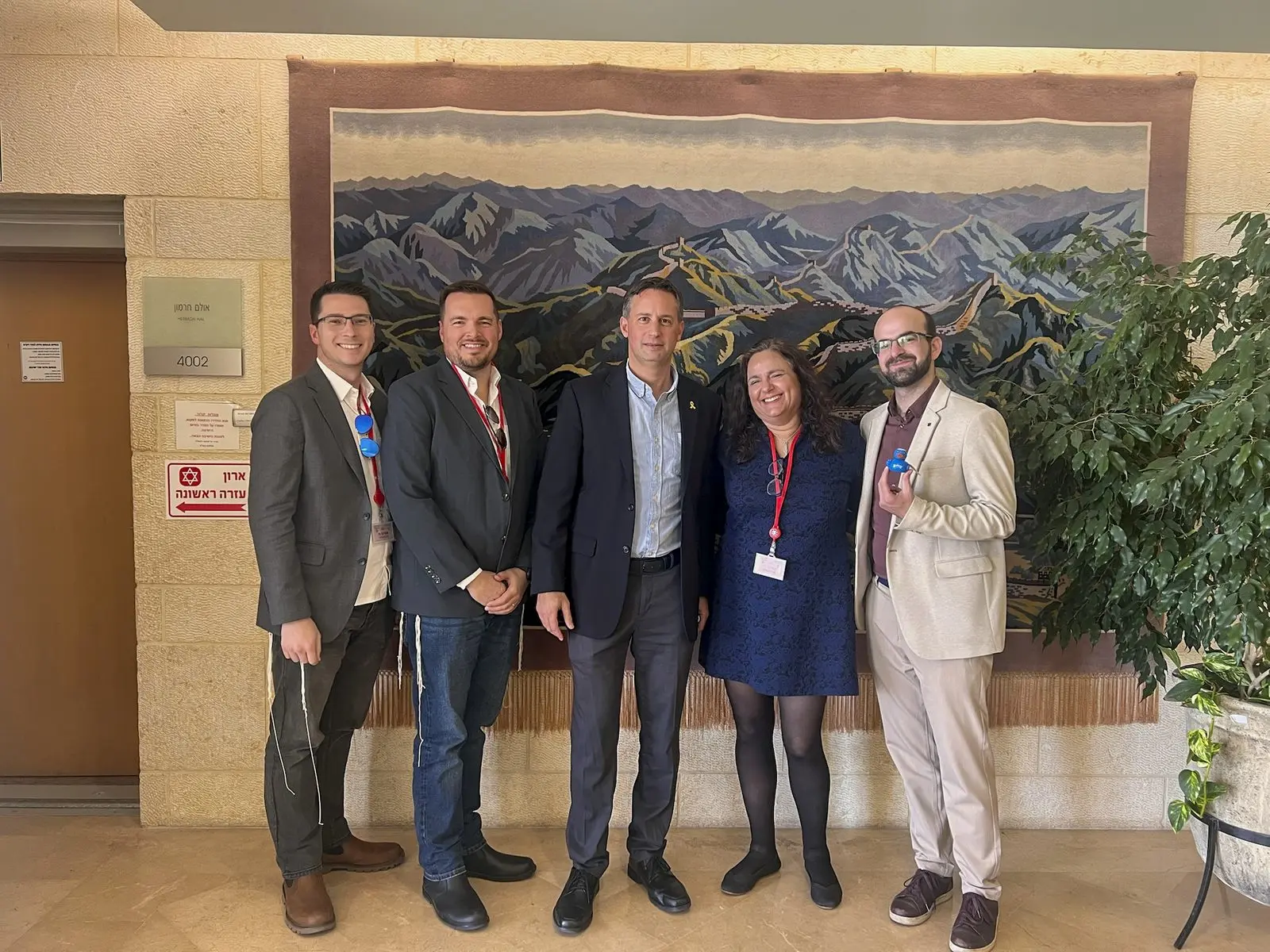 An Atlanta Israel Coalition delegation gathers for a group photo in front of a mural of the Israeli landscape.