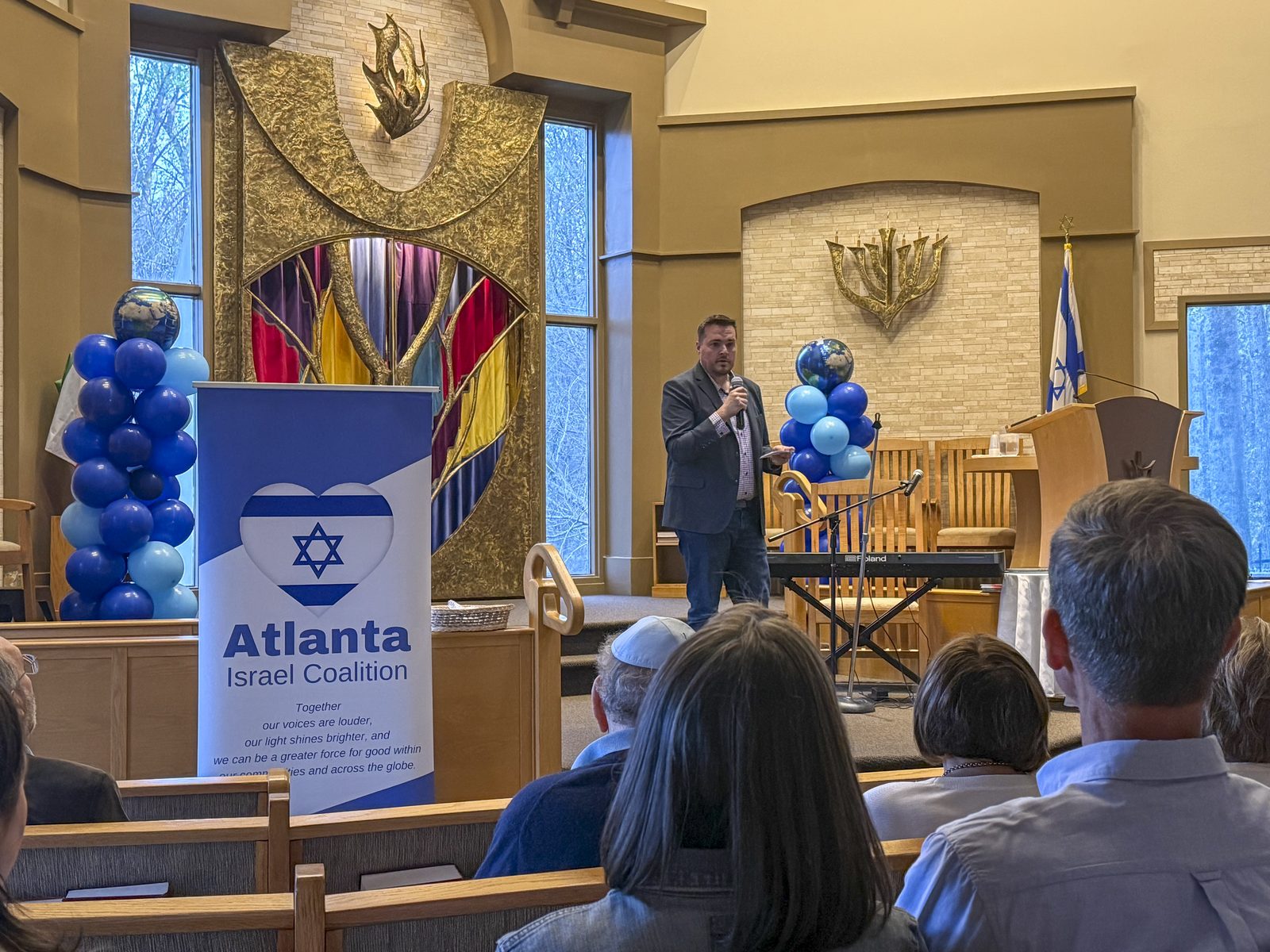 Community members fill a synagogue sanctuary decorated with blue balloons at an Atlanta Israel Coalition gathering.