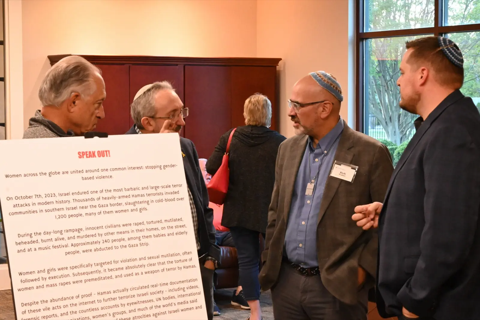 Attendees in conversation beside an informational display at an Atlanta Israel Coalition event.
